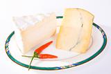 Two cuts of French cheese with red chili peppers