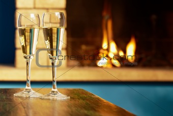 two flutes filled with champagne near fireplace