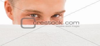 Young man behind white towel