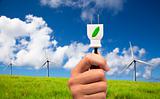 Hand hold eco power plug and Wind turbines on blue sky