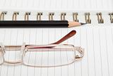 A diary with a pencil and glasses