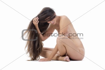 beautiful nude woman with long hair sitting on the floor - isolated on white