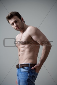 young shirtless musculous man in jeans looking - isolated on gray