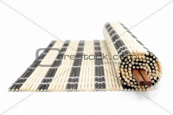 Rolled bamboo mat and chopsticks isolated on white