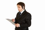 Serious businessman with headset checking notes in document
