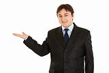 Smiling young  businessman presenting something on empty hand
