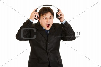 Shocked modern businessman removes headphones
