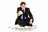 Successful businessman sitting on floor surrounded by money
