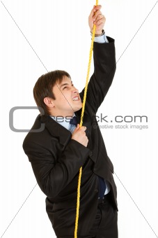 Stubborn businessman climbing up on rope
