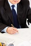 Businessman sitting at office desk and signing document. Close -up. 
