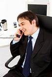 Smiling young businessman talking on  telephone in office
