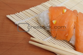 Salmon sushi and chopsticks on bamboo mat