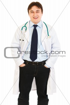 Smiling doctor with stethoscope keeping his hands in pockets

