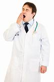 Tired young medical doctor yawning
