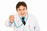 Smiling young medical doctor holding up stethoscope
