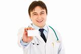 Smiling medical doctor holding  blank business card in hand
