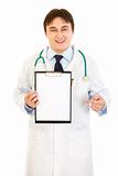 Smiling medical doctor pointing finger at blank clipboard
