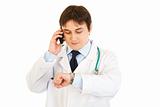 Medical doctor talking on mobile and looking at his watch
