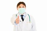 Medical doctor with mask on face showing  thumbs up gesture

