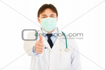 Medical doctor with mask on face showing  thumbs up gesture

