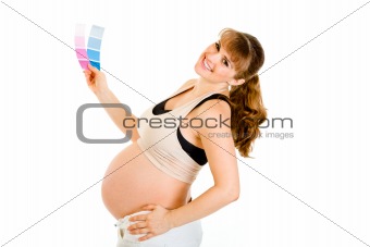Happy pregnant woman holding color paint samples

