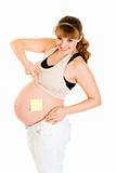 Smiling pregnant woman pointing on blank sticky note on her belly
