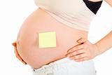 Pregnant woman with blank sticky note on her belly. Close-up.
