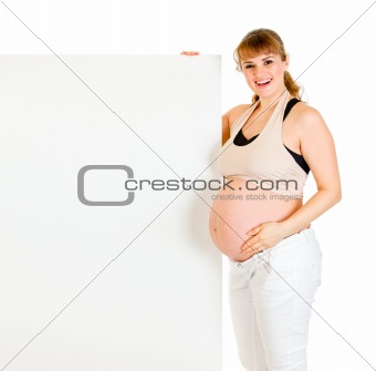 Smiling beautiful pregnant woman holding blank billboard

