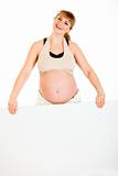 Happy beautiful pregnant woman holding blank billboard
