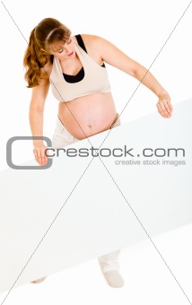 Interested pregnant woman holding blank billboard

