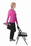 Active senior woman doing leg stretch with chair