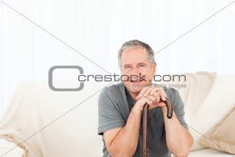 Mature man with his walking stick on his bed