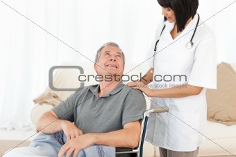 Man in his wheelchair with his nurse at home