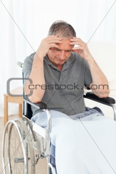 Senior in his wheelchair having a headache