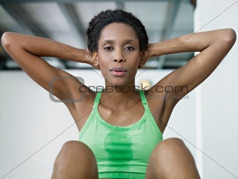 african woman doing series of crunch in gym