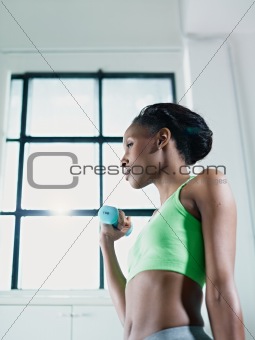 african woman exercising with small weights in gym