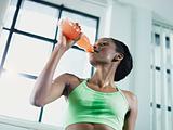 african woman in gym drinking energy drink