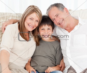 A little boy with his grandparents looking at the camera 