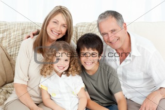 A happy family on their sofa looking at the camera 