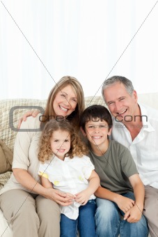 A happy family on their sofa looking at the camera 