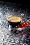 Espresso cofee with currants on black glass table
