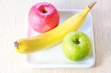 Banana, green and red apples on plate