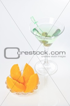 Peach dessert and green alcohol cocktail with martini and olives