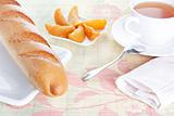 Baguette on plate, peach dessert and a cup of tea