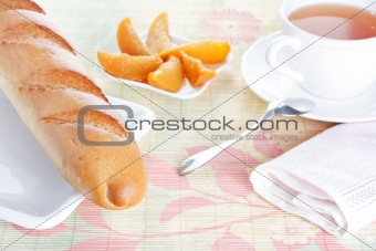 Baguette on plate, peach dessert and a cup of tea