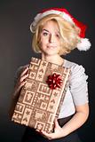 Cute girl in a Christmas hat with a gift box 