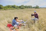 happy couple enjoying countryside picnic in long grass