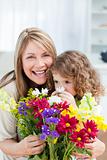 Little girl smelling flowers while her grandmother is smilling