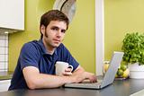 Young Man with Warm Drink at Computer