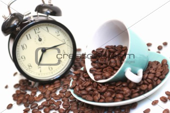 Cup with coffee grains and a black alarm clock